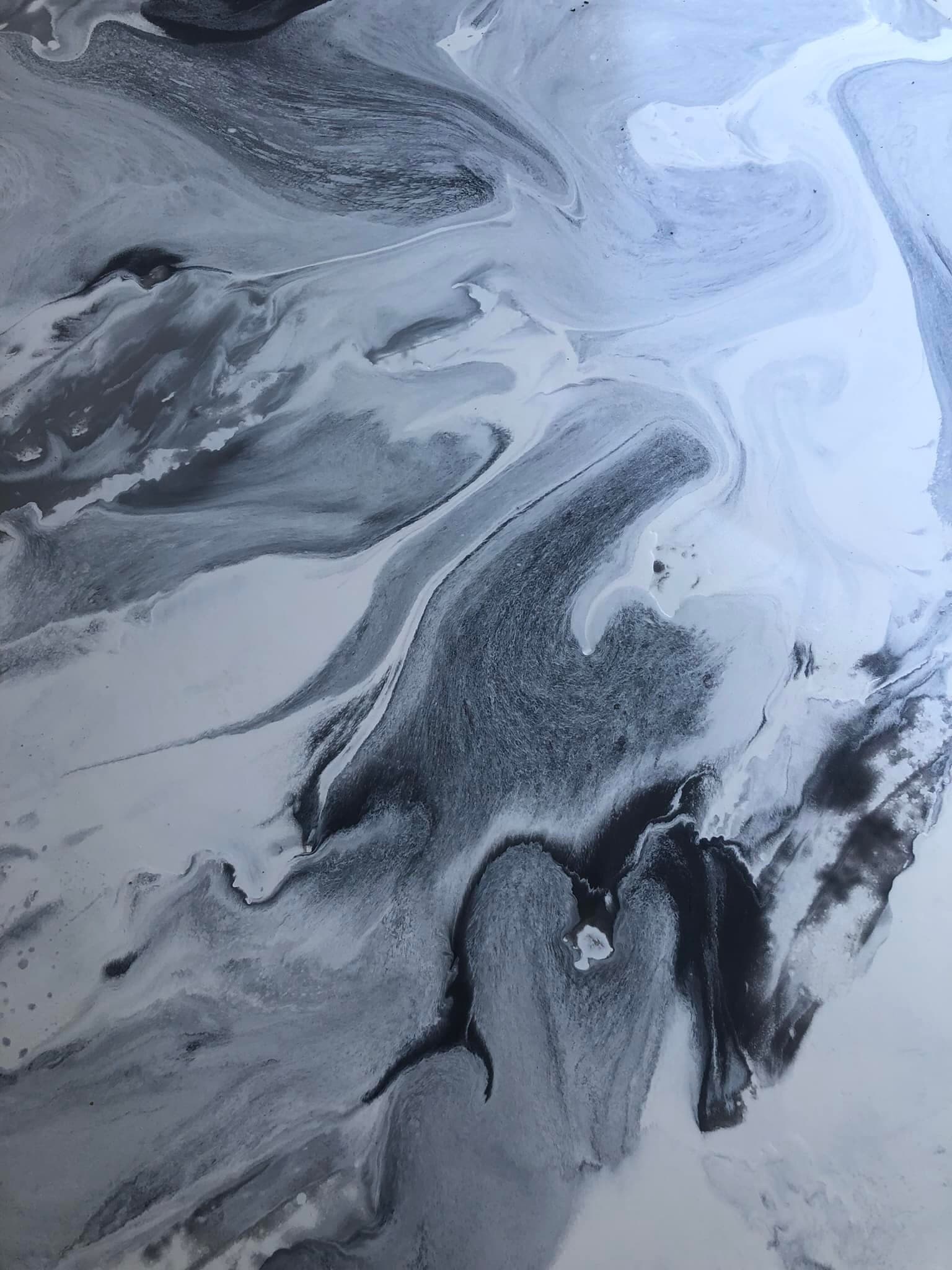 Close detail of black-and-white metallic epoxy swirling like poured marble.