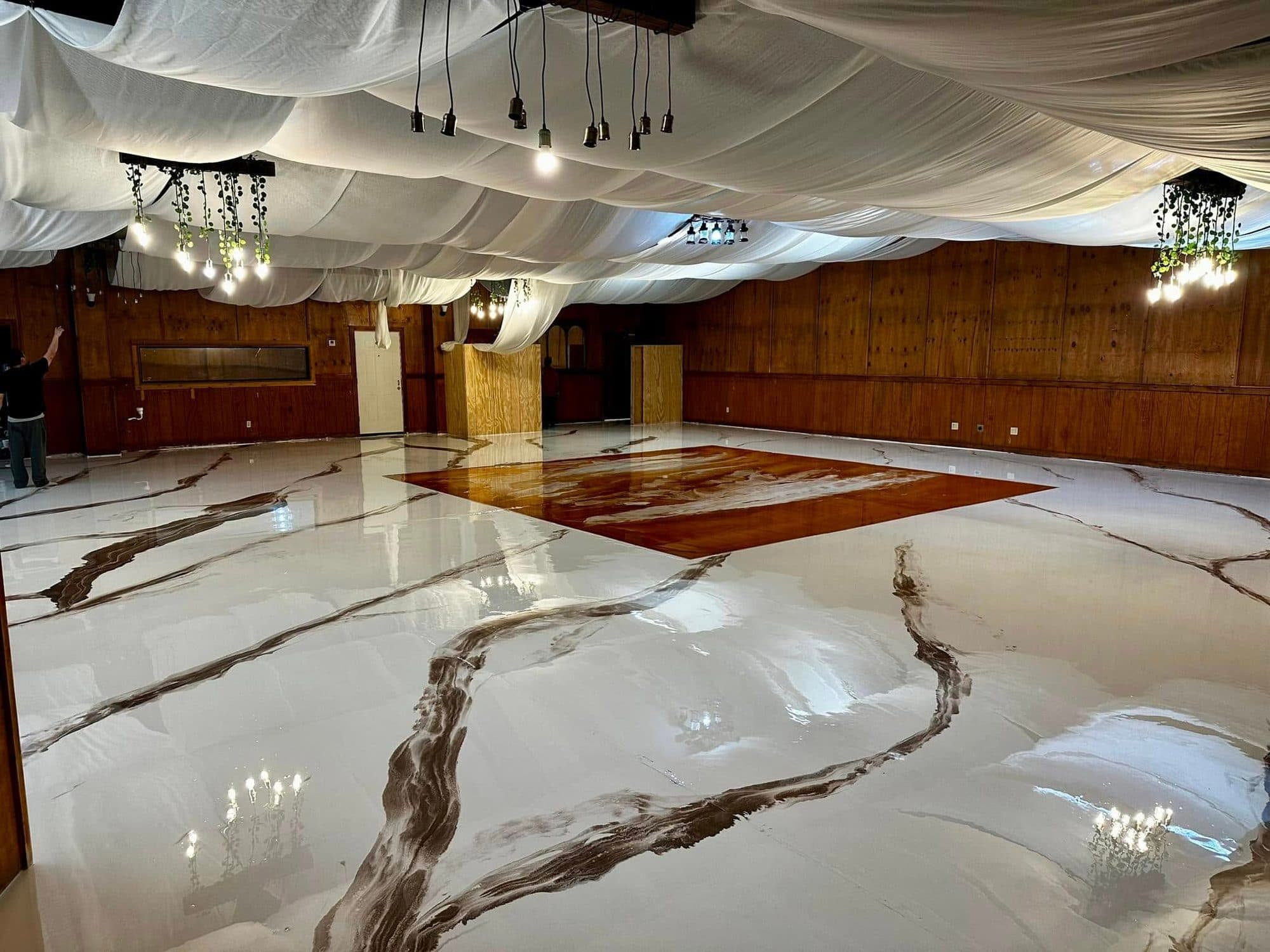 Marbled white metallic epoxy floor filling a large draped event hall.