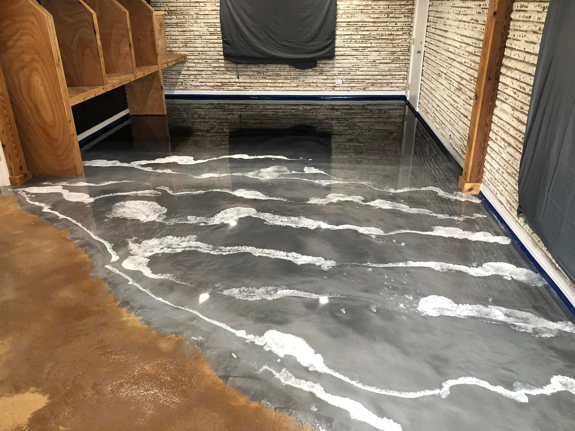 A grey metallic epoxy floor with a white shoreline pattern flowing across a workshop.